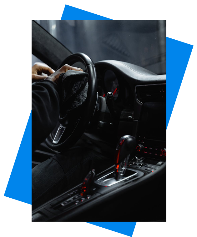 We Provide Quality Car Washing Services Close-up of a person cleaning a car's dashboard and steering wheel, focused on interior maintenance.